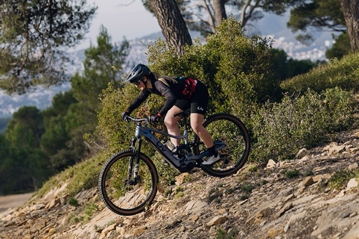 Jezdkyně na Liv Embolden E+ 2027 sjíždí technickou kamenitou pasáž